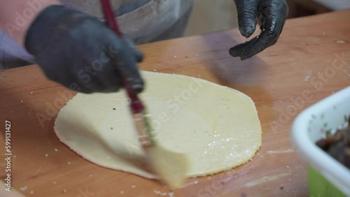 Close-up of brushing flattened raw pastry dough with butter, making Flaouna. photo