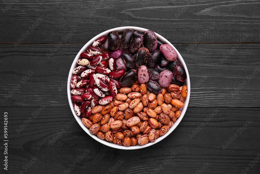 Different kinds of dry kidney beans in bowl on wooden table, top view Different kinds of dry kidney beans in bowl on wooden table, top view