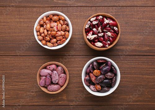 Different kinds of dry kidney beans on wooden table, flat lay