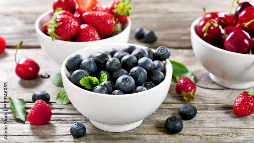 bowl of berries fruits- finger holding blueberry bowl of berries fruits- finger holding blueberry