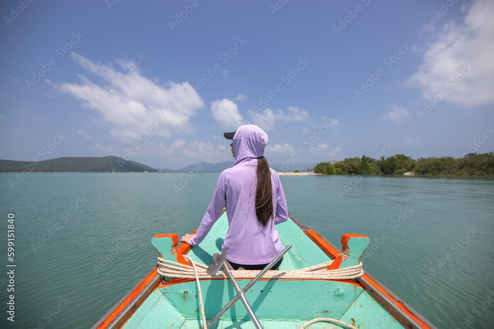 Woman riding on the boat dressed in sun protection hoodie, summer heat