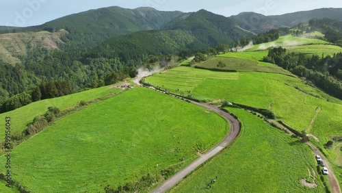 Car races down lush mountainside on dirt road during Azores Rally Graminhais stage, Tour European Rally. Aerial view photo