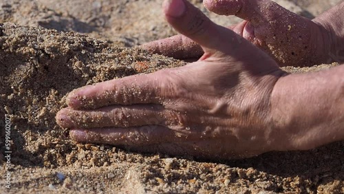 Close up shot of a man's hands shaping wet sand beach, playing with sand, building sandcastle. Family vacation at the seashore concept photo