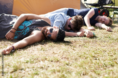 Drunk sleeping, hangover and party people on camping park at music festival with alcohol. Field, ground and lawn with a tent and youth on grass with male friends and man camper at concert outdoor