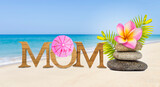 Mother's day card background idea, tropical style, mom wooden font with flower and paper umbrella over blurred summer beach background