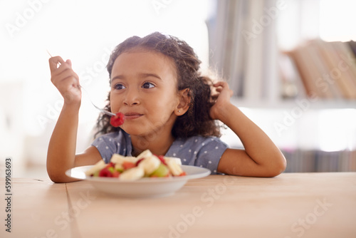 Eating child, breakfast and fruit salad at home with happiness and wellness meal with a smile. House, nutrition and young girl with healthy food and fruits of a hungry kid in the morning at a table