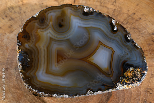 Piękny unikatowy ciemny kamień szlachetny - agat szlifowany. Ujęcie z bliska na drewnianej desce 
