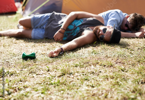 Drunk, sleeping and men on camping ground at a music festival with alcohol. Field, drinking and lawn with a tent and youth on grass with people and man camper at concert outdoor with cans