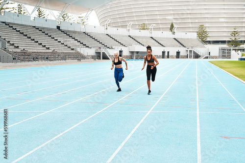 Be stronger than your excuses. Full length shot of two attractive young athletes running a track field together during an outdoor workout session.