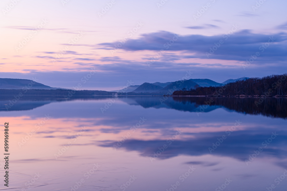 風景を湖面に反射する早朝の湖。北海道の屈斜路湖。