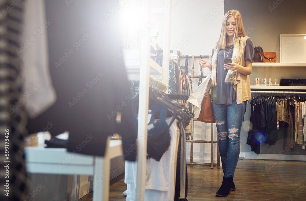 Obraz premium I hope people know about this awesome store. a young woman using her cellphone while out shopping.