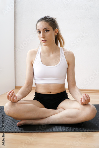 Fototapeta Naklejka Na Ścianę i Meble -  Sporty young woman doing yoga and meditation at home	
