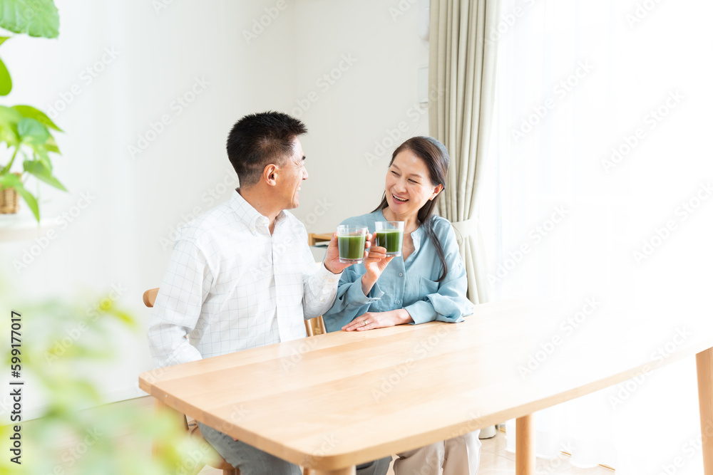 Obraz premium リビングで青汁を持つシニア夫婦