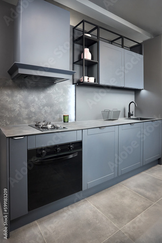 Blue grey contemporary kitchen linearlayout with hood two burners gas cooker hob oven and built in dishwasher machine and square black sink and tap compact high pressure laminate HPL countertop.