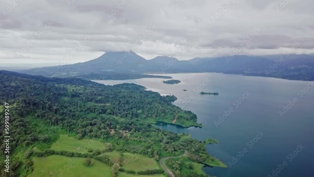 aerial view of Arenal Volcano, towering over lake Arenal and some islands, Arenal Volcano national park, daytime,low clouds Establishing