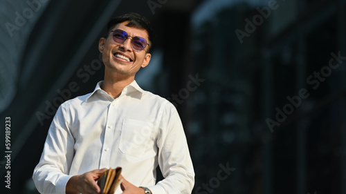 Portrait businessman in photochromic glasses standing outside building. Modern lifestyle and technology concept photo