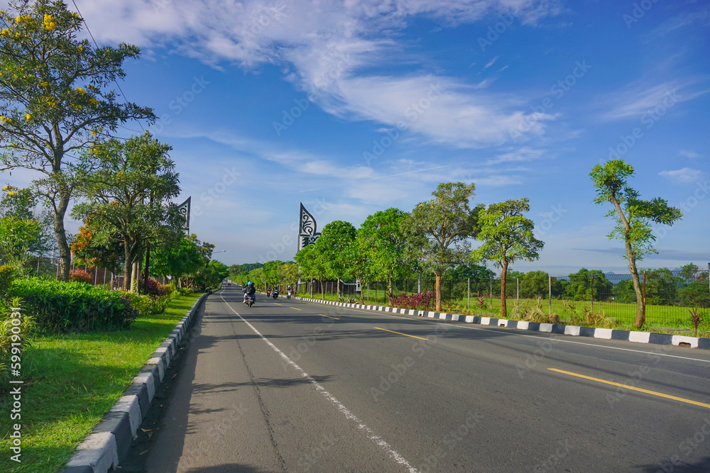 Empty highway condition in the morning with clear sky and beautiful park by the roadside.