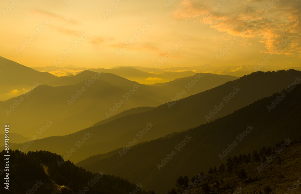 Orange sunset in the highlands. Foggy view of mountain range. Nature background