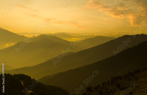 Orange sunset in the highlands. Foggy view of mountain range. Nature background