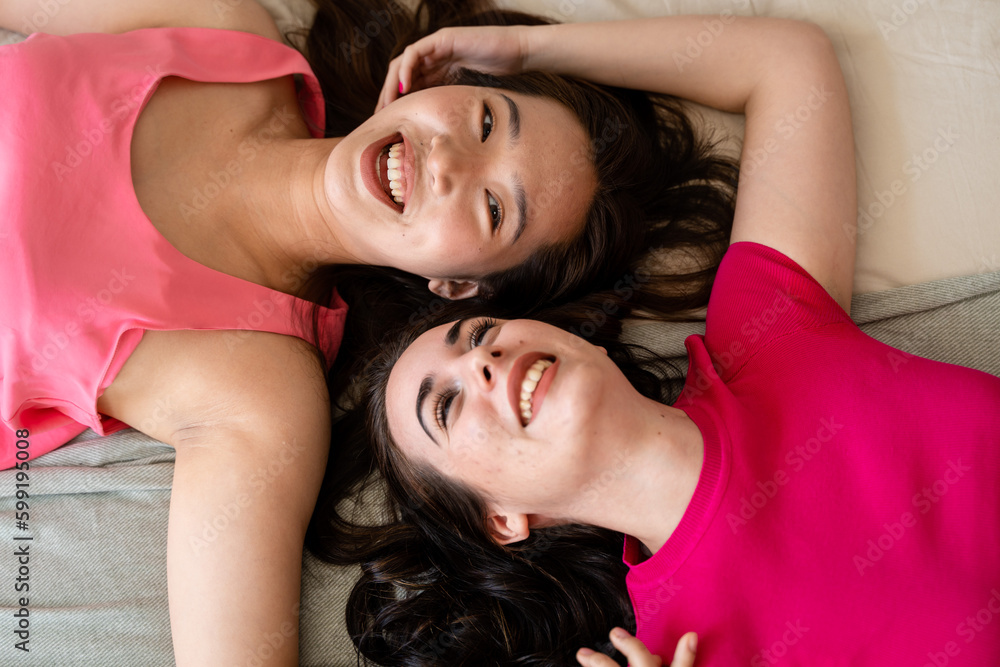 Multiracial couple of women lying side by side in bed. Multiracial couple of women lying side by side in bed.