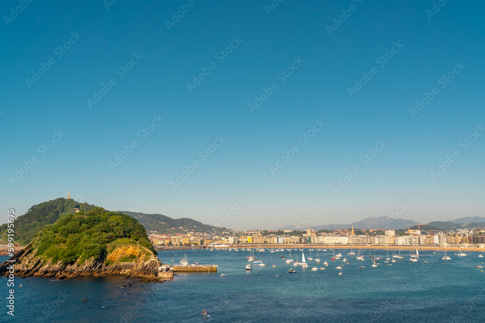 High angle view of San Sebastian - Donostia city at sunset. Situated in north of Spain, Basque Country. Famous travel destination. View of La Concha Bay, Santa Clara Island. Warm sunset colours  