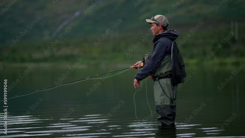 Side view of young man pulling line on fly fishing rod in still water Side view of young man pulling line on fly fishing rod in still water