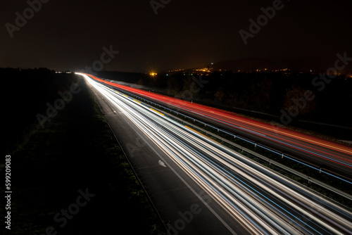 Cars light trails on a straight highway at sunset. Night traffic trails, Motion blur, Night city road with traffic headlight motion. 