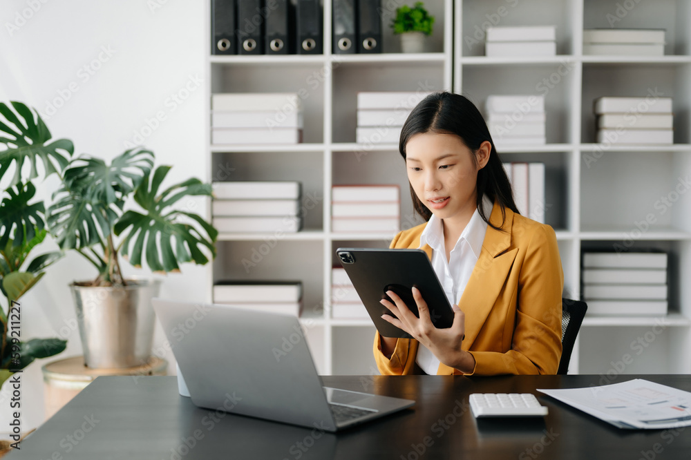 Asian businesswoman working in the modern office with working notepad, tablet and laptop documents Asian businesswoman working in the modern office with working notepad, tablet and laptop documents
