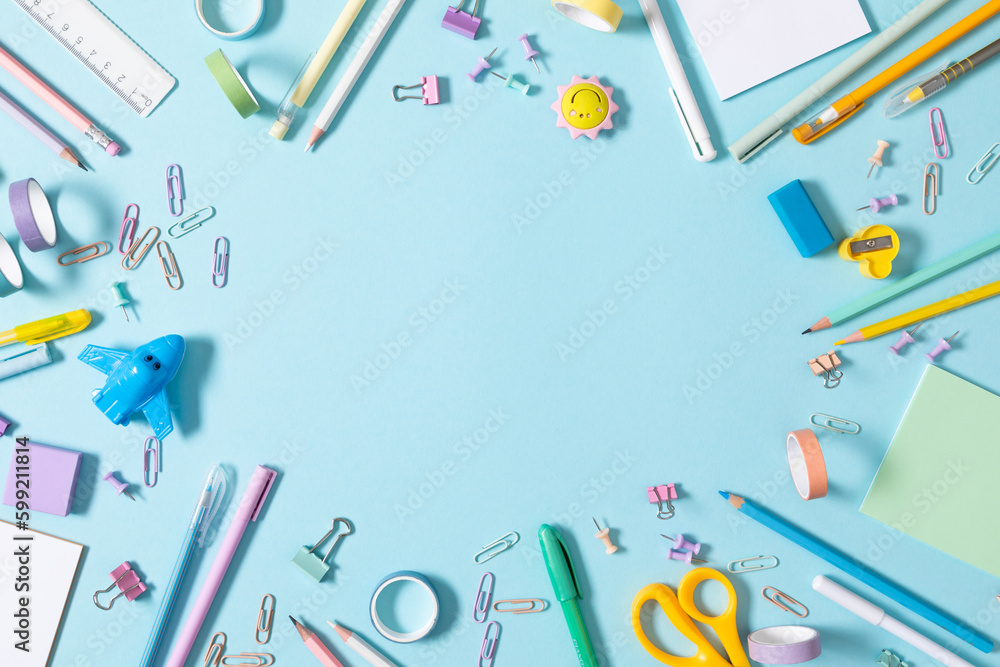 Back to school concept. Flat lay top view of scattered stationery notepad pens pencils paper clips airplane sticky tape note paper isolated on pastel blue background Back to school concept. Flat lay top view of scattered stationery notepad pens pencils paper clips airplane sticky tape note paper isolated on pastel blue background