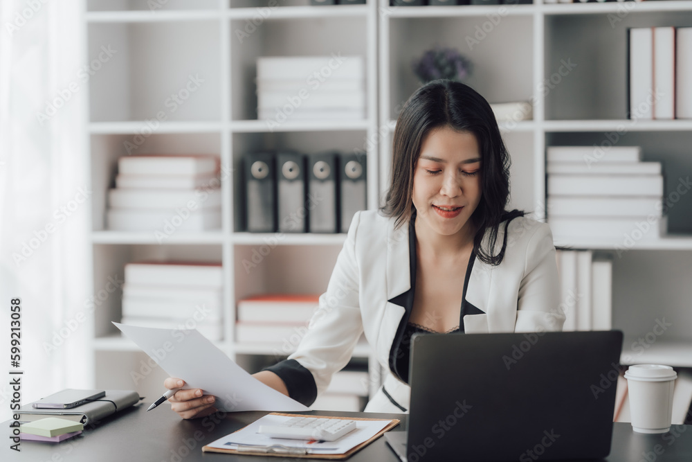 Cheerful business lady working on laptop in office, Asian happy beautiful businesswoman in formal suit work in workplace. Attractive female employee office worker smile. Cheerful business lady working on laptop in office, Asian happy beautiful businesswoman in formal suit work in workplace. Attractive female employee office worker smile.