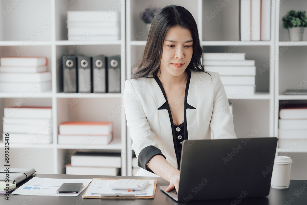 Cheerful business lady working on laptop in office, Asian happy beautiful businesswoman in formal suit work in workplace. Attractive female employee office worker smile. Cheerful business lady working on laptop in office, Asian happy beautiful businesswoman in formal suit work in workplace. Attractive female employee office worker smile.