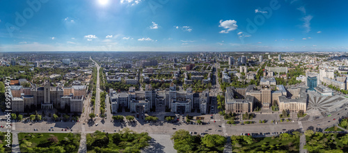 Aerial look down wide panorama on Derzhprom and Karazin National University buildings on Freedom Square with circle fountain, spring greenery and blue sunny sky in Kharkiv, Ukraine