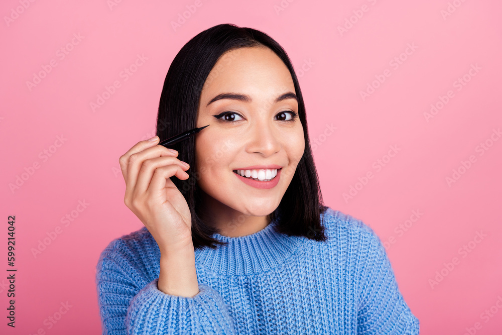 Portrait of cute lovely person toothy smile hand hold apply eyeliner isolated on pink color background Portrait of cute lovely person toothy smile hand hold apply eyeliner isolated on pink color background