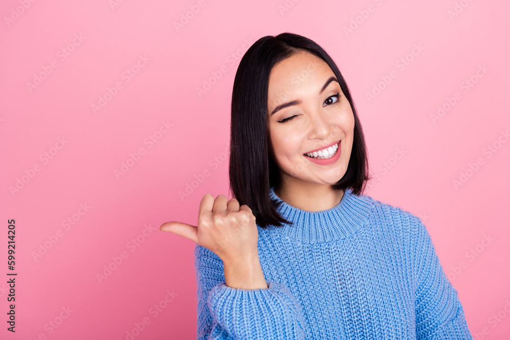Portrait of cunning tricky girl with bob hairstyle wear blue sweater directing empty space sale winking isolated on pink color background Portrait of cunning tricky girl with bob hairstyle wear blue sweater directing empty space sale winking isolated on pink color background