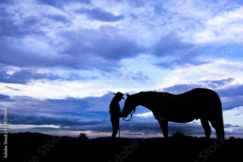 Silhouette of female teen and horse against clouds on farm