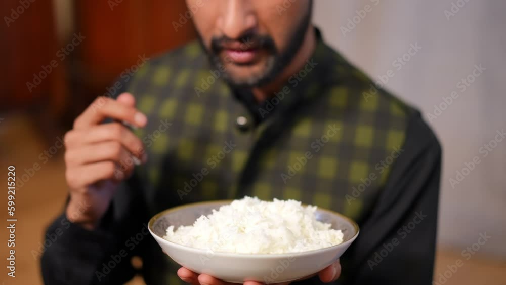 Unrecognizable Middle Eastern man eating white rice with hands indoors