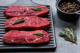 Fresh meat. Raw beef steaks with rosemary and spices on a stylish blackboard. Flat top view.