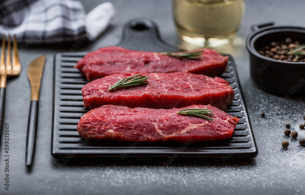 Fresh meat. Raw beef steaks with rosemary and spices on a stylish blackboard. Flat top view. Fresh meat. Raw beef steaks with rosemary and spices on a stylish blackboard. Flat top view.
