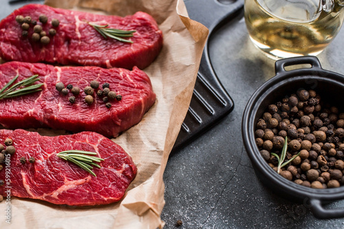 Fresh meat. Raw beef steaks with rosemary and spices on parchment paper on a stylish board. Flat top view.