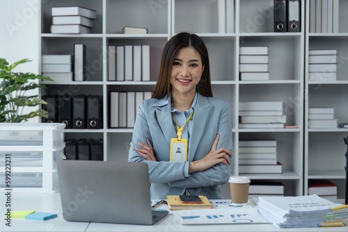 Business woman portrait and smile at desk in office for paperwork, laptop. Happy business young confident female worker with pride planning project at table in startup company © Natee Meepian