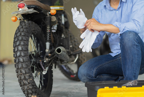 Mechanic working in motorcycle repair shop, wearing protective gloves. Bike Maintenance Concept.