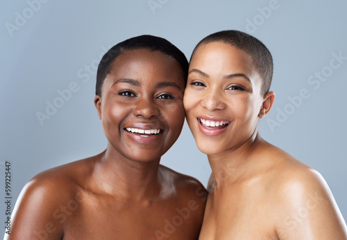 Its all smiles when were together. Portrait of two beautiful young women standing close to each other against a grey background.