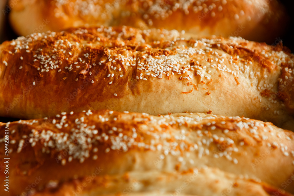 Close up shot homemade food baking concept. Fresh hot soft fluffy ginger golden brown sesame seeds buns pie bread dessert pastry in loaf pan. Bakery products, image with copy space.
