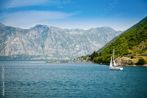 View of famous Bay of Kotor and a floating white yacht on a beautiful sunny day
