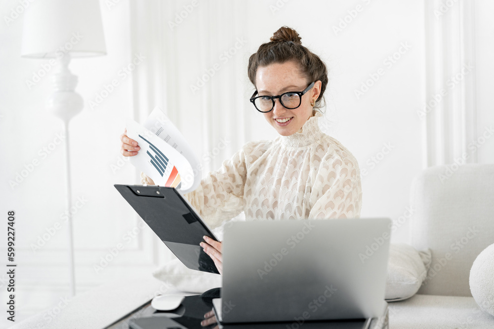 Financial director a woman with glasses is smart looking at charts, a report in the company for a month and a year. Using a laptop computer on the desktop. Financial director a woman with glasses is smart looking at charts, a report in the company for a month and a year. Using a laptop computer on the desktop.