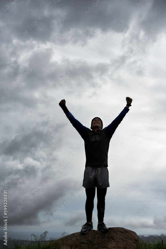 Triumph at the top. A young man celebrating at the top of a mountain after reaching the summit. Triumph at the top. A young man celebrating at the top of a mountain after reaching the summit.