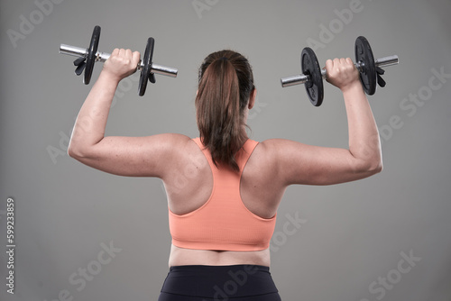 Strong plus size woman working out with dumbbells