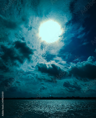 Beautiful moonlit night with lots of cloud and the moon reflection in river in Bangladesh  photo