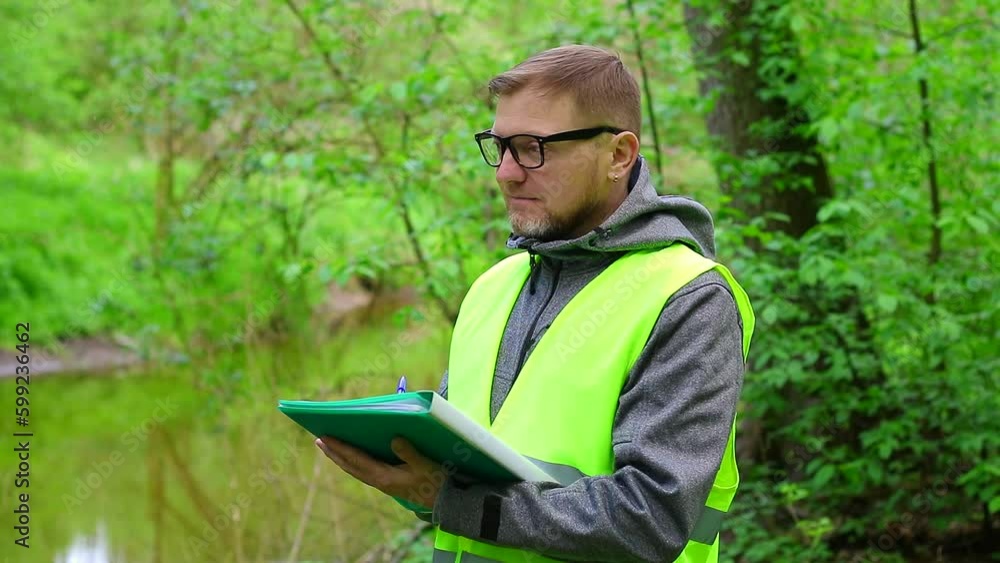 Male ecologist makes records of the state of the environment forest river. Environmental control. Male ecologist makes records of the state of the environment forest river. Environmental control.