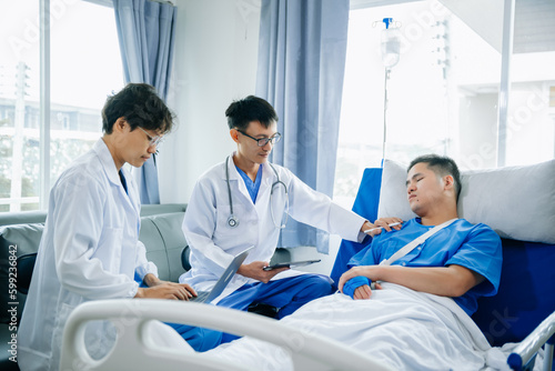 Hospital Ward Male and  Male Professional Asian Doctors Talk with a Patient  Give Health Care Advice  Recommend Treatment Plan  with Advanced Equipment